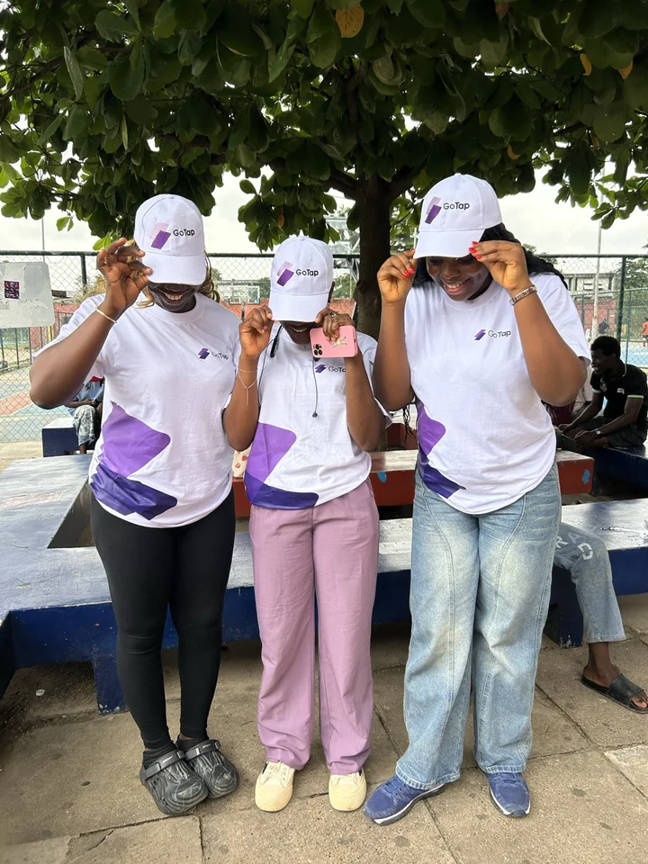 Three GoTap team members wearing GoTap shirts and caps under a campus tree.